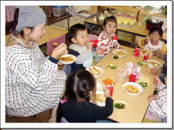 保育者と友達と食べている写真