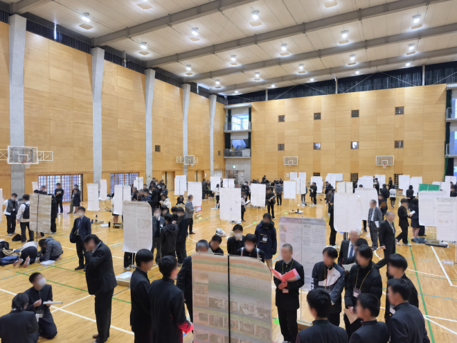 令和6年度CCSS Fairで、体育館内のポスター前で説明している様子(顔ぼかし加工済み)