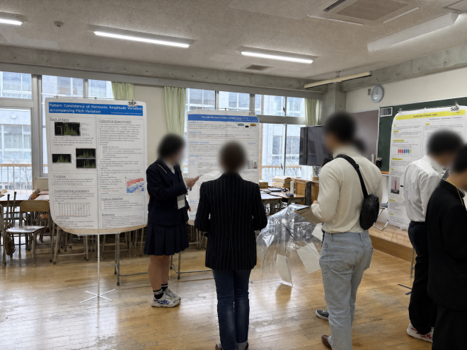 令和7年度CCSS Fairで、教室内のポスター前で発表している様子(顔ぼかし加工済み)